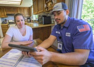Apollo plumbing tech working with homeowner at her kitchen table, going over her estimate.